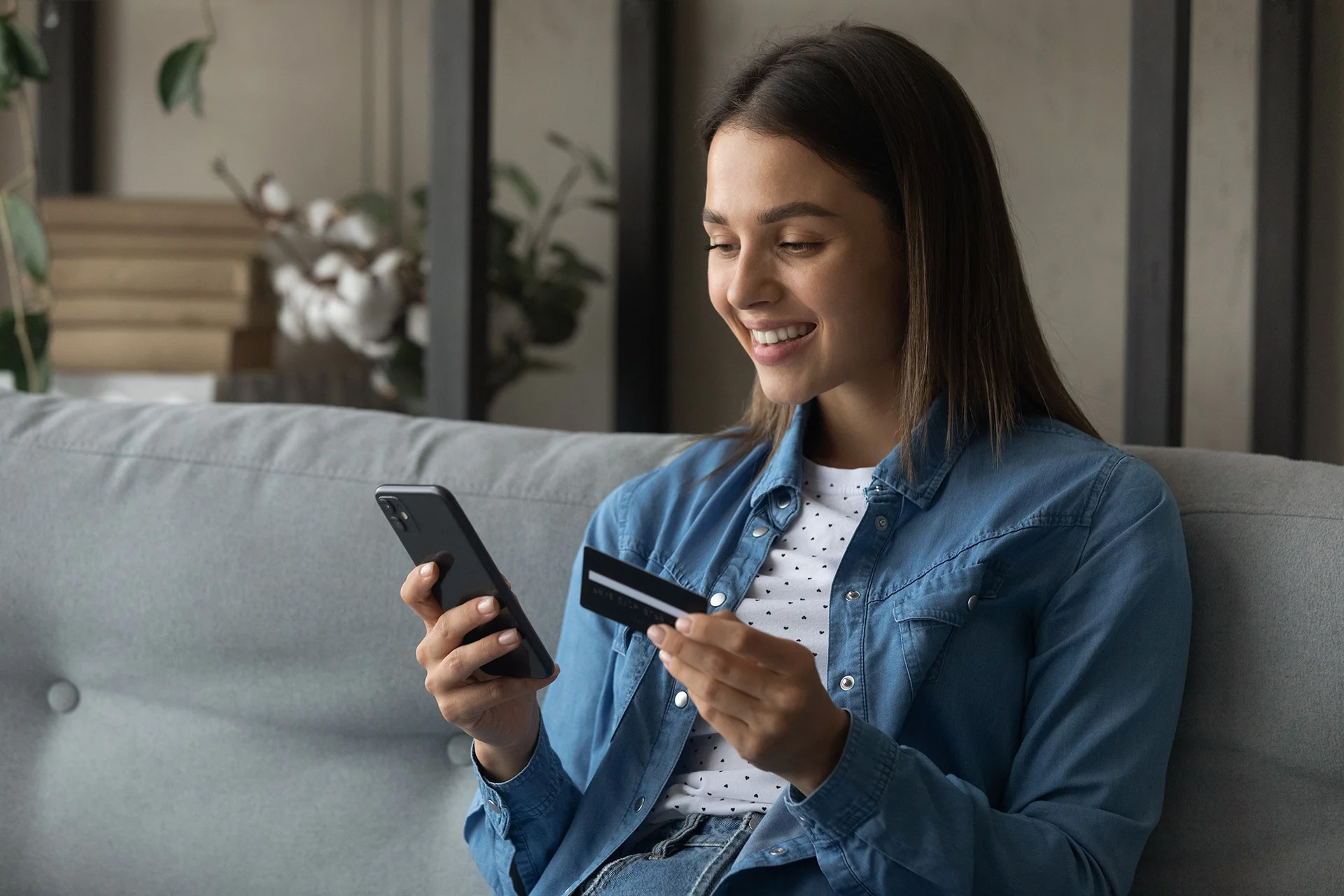 woman holding cell phone and debit card