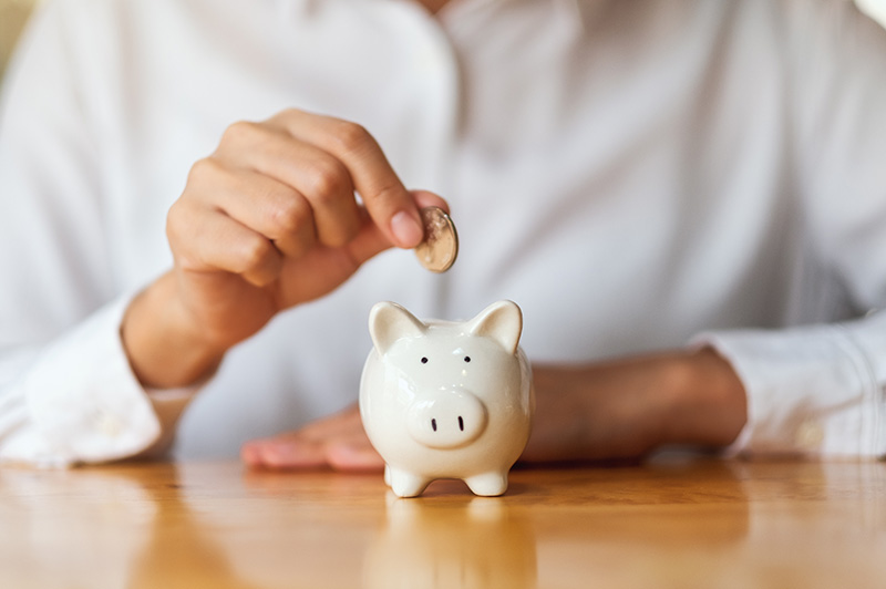 person putting coins in a piggy bank